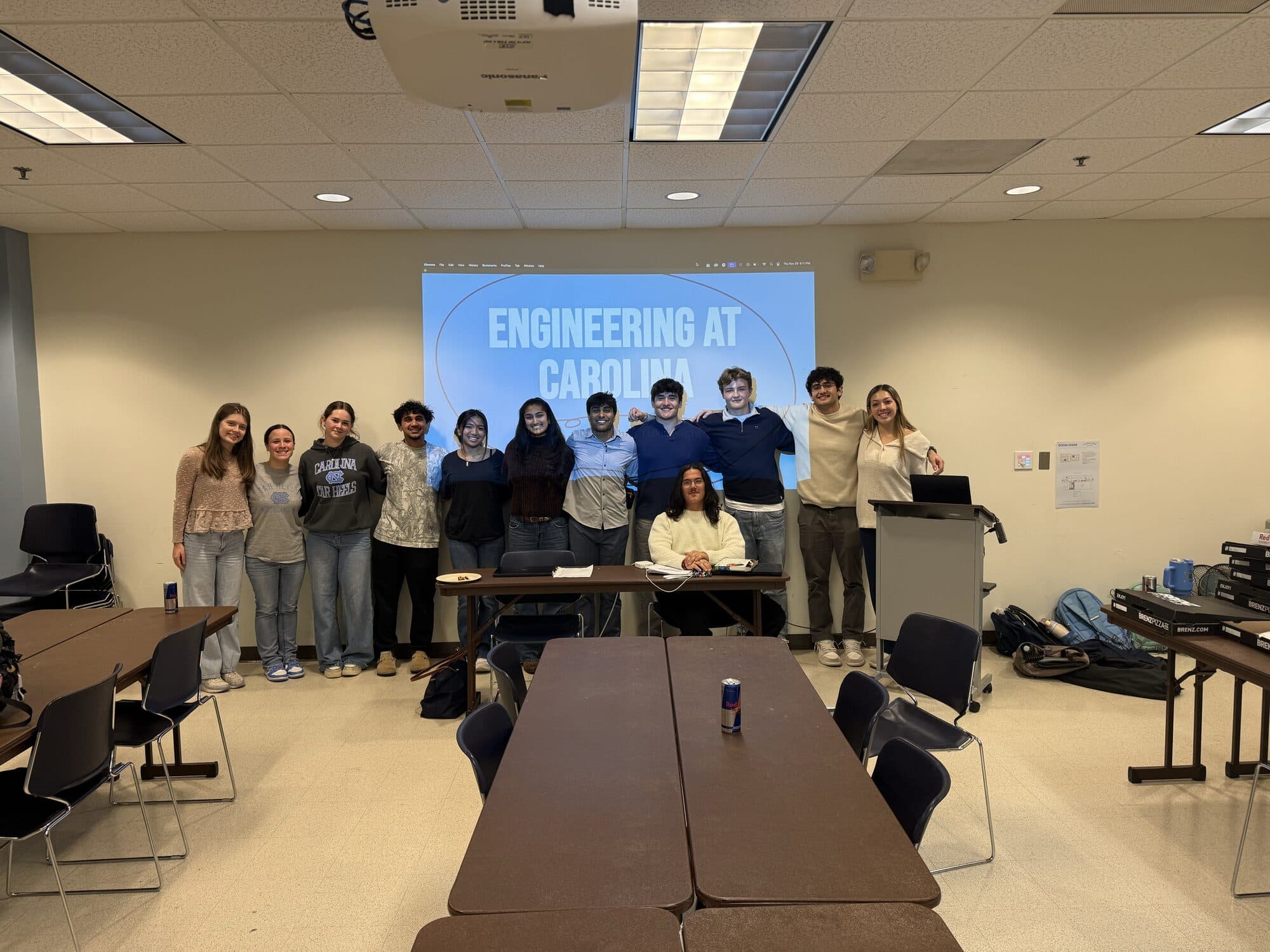 Trivia Night: a group of students standing in front of a projected slide reading Engineering at Carolina, one of them seated at the table in front.